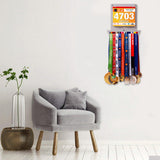 Wall-mounted Race Bib Holder + Medal Hanger Display Rack V1 by Victory Hangers® displayed in a modern living room, showcasing medals and race bibs.