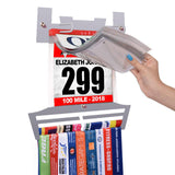 Close-up of Race Bib Holder + Medal Hanger Display Rack V2 with hand flipping through clear vinyl sleeves for organizing race bibs efficiently.